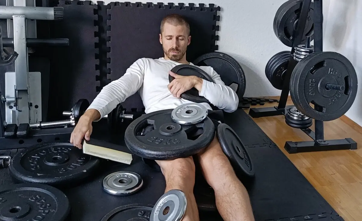 Fitnesstrainer Christopher Le begraben unter Hantelscheiben nach einem intensiven Krafttraining.