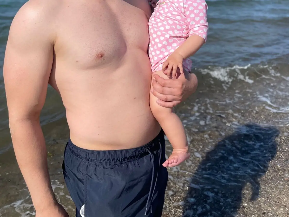 Dad Bod am Strand, sichtbarer Vaterbauch.