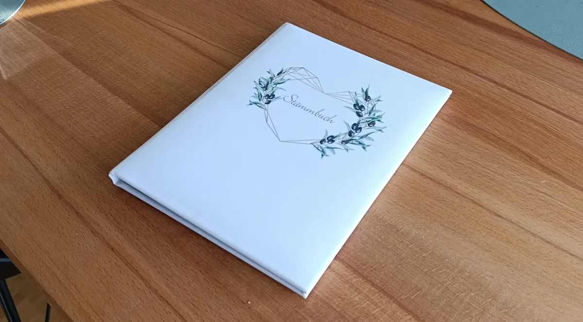 Ein Stammbuch liegt auf einem Holztisch und steht scherzhaft dafür, dass man auch, wenn man noch kein Vater ist einen sogenannten Dad Bod haben kann.