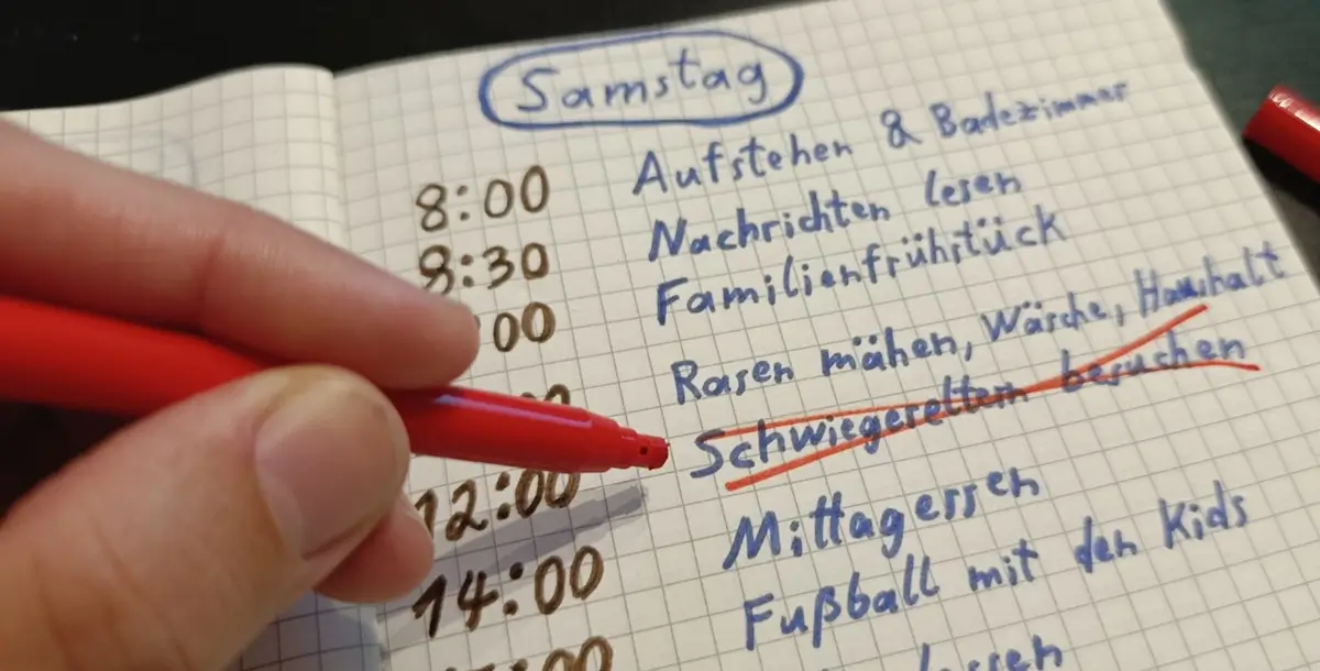 Ein Vater streicht einen Termin (Besuch bei den Schwiegereltern) aus seiner Planung im Notizbuch, um Zeit und Raum für eine Trainingseinheit zu schaffen.