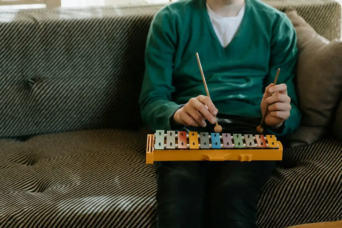 Ein Xylophon wird auf einem Sofa gespielt als humorvolles Beispiel für ein wichtiges Hobby, das trotz der Zeitknappheit neben dem Krafttraining weiter betrieben werden soll.